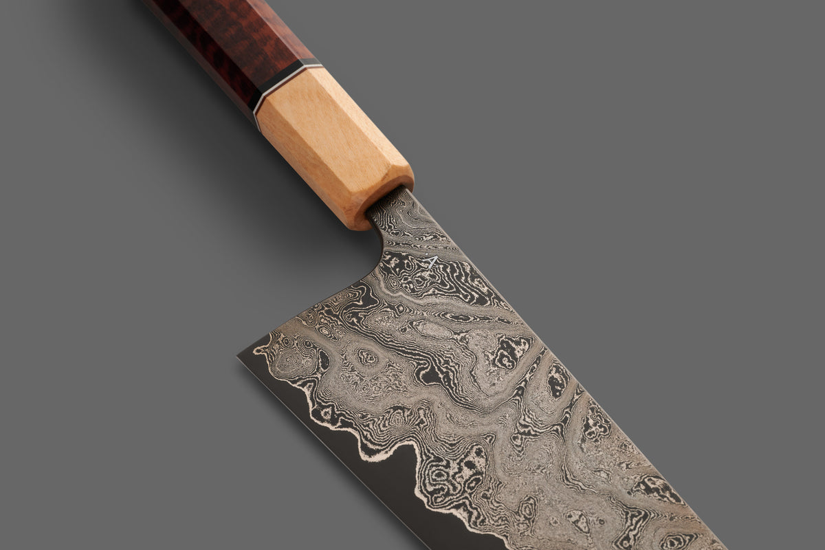 Close-up of a handmade Damascus steel kitchen knife with an octagonal wooden handle